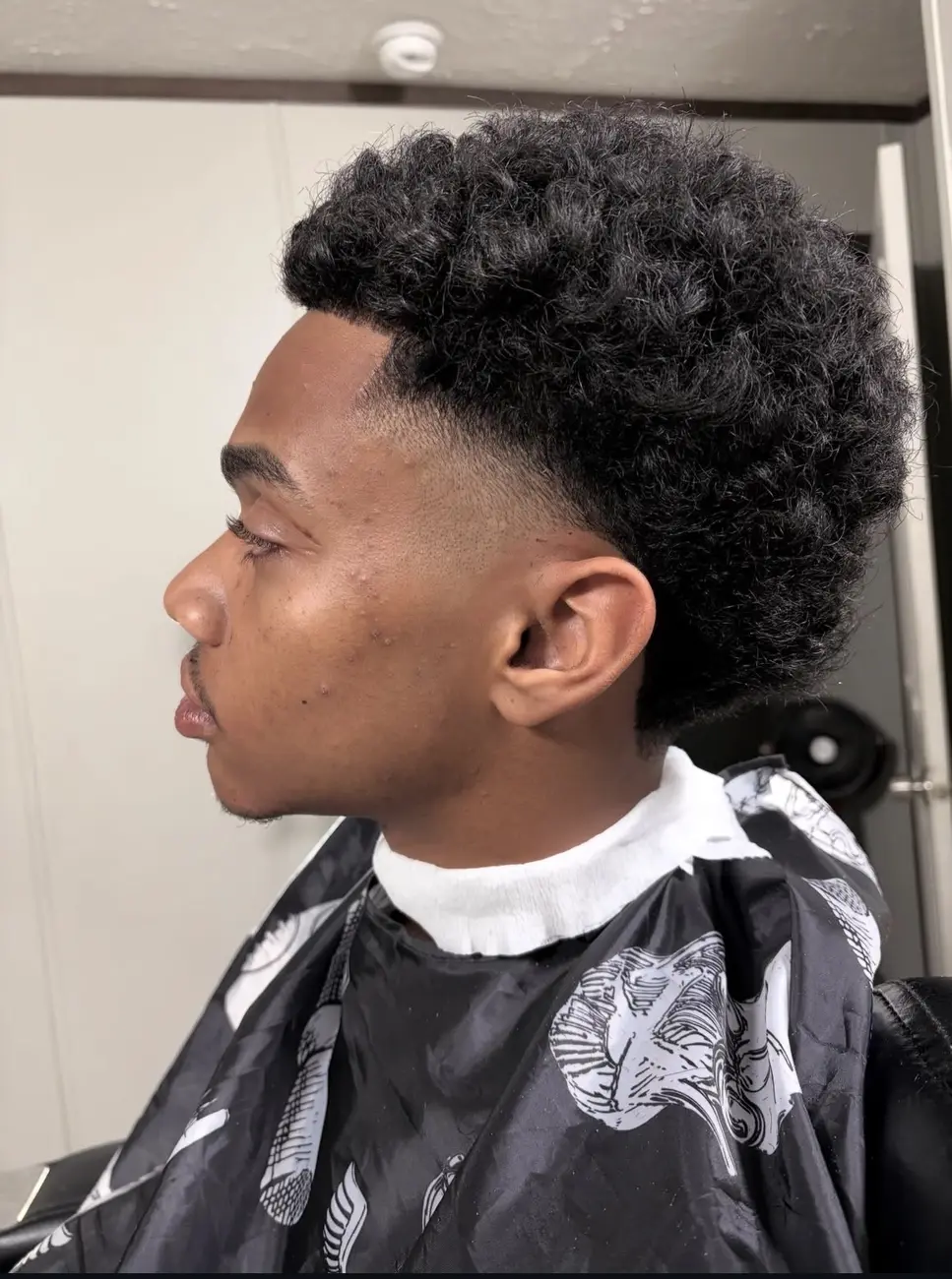 Profile of a rounded curly top with a low fade
